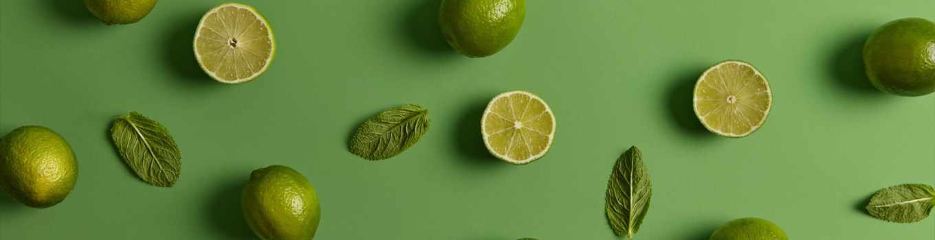 چند عدد لیمو ترش و برگ نعناع در پس زمینه سبز رنگ
